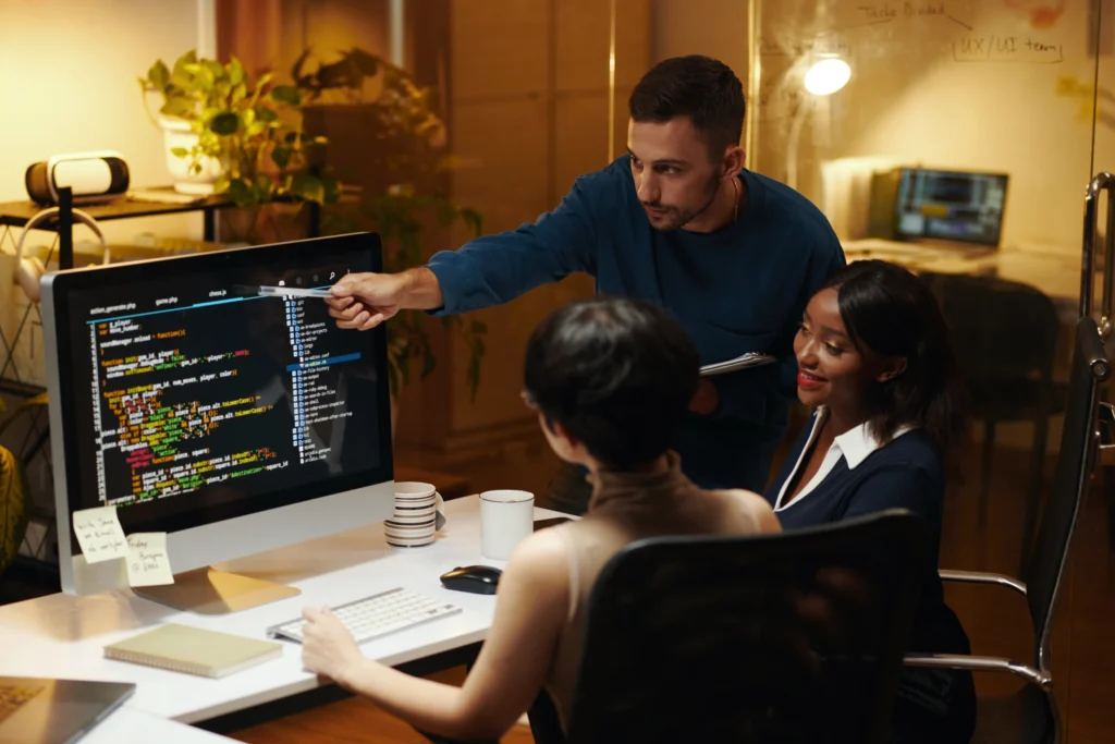 Software development team reviewing custom code on a large screen while building scalable business solutions